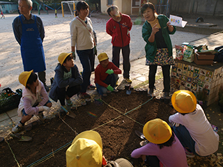 ①花壇に植える花の説明を真剣に聞く子供たち
